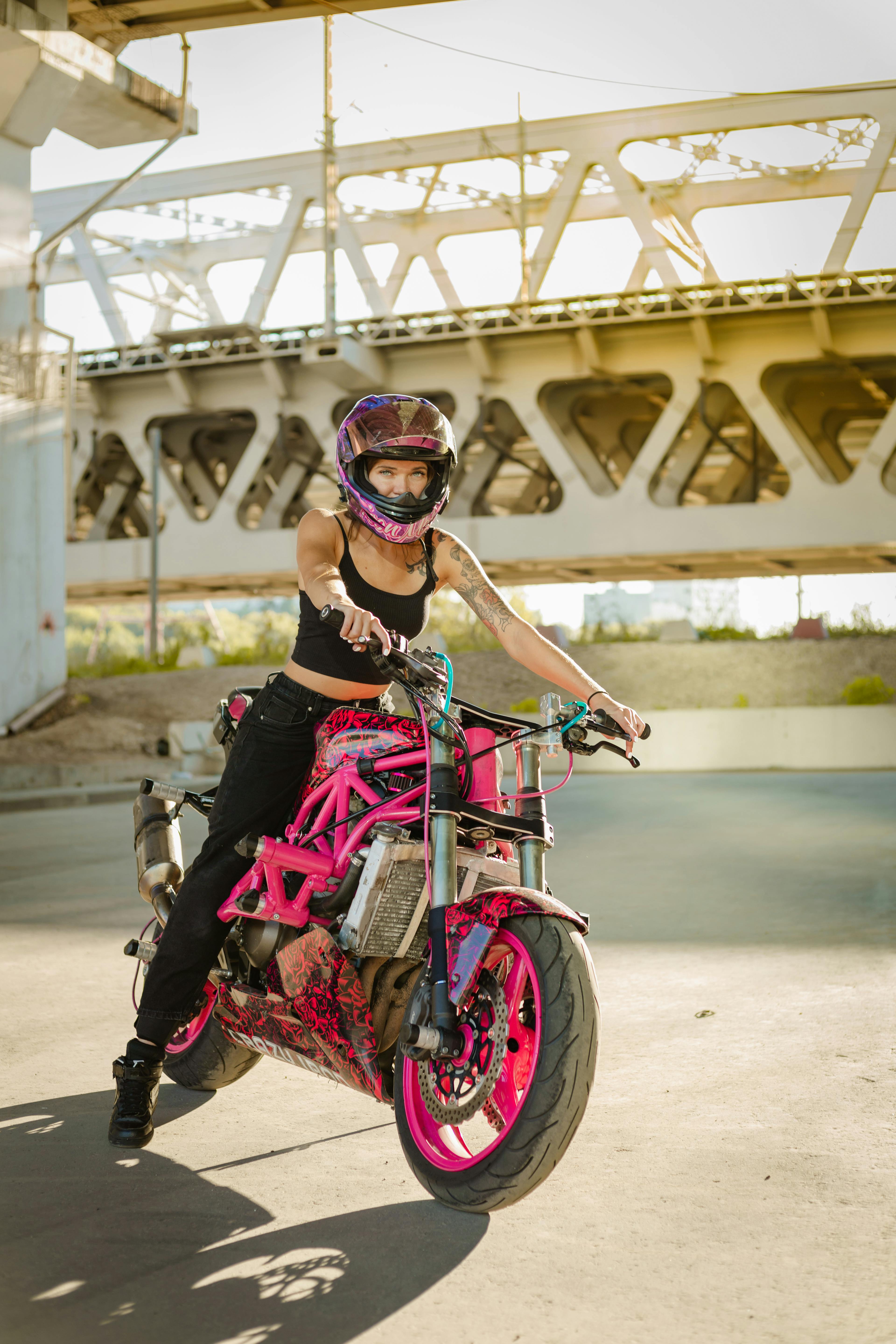 une femme sur une moto rose avec un casque de moto