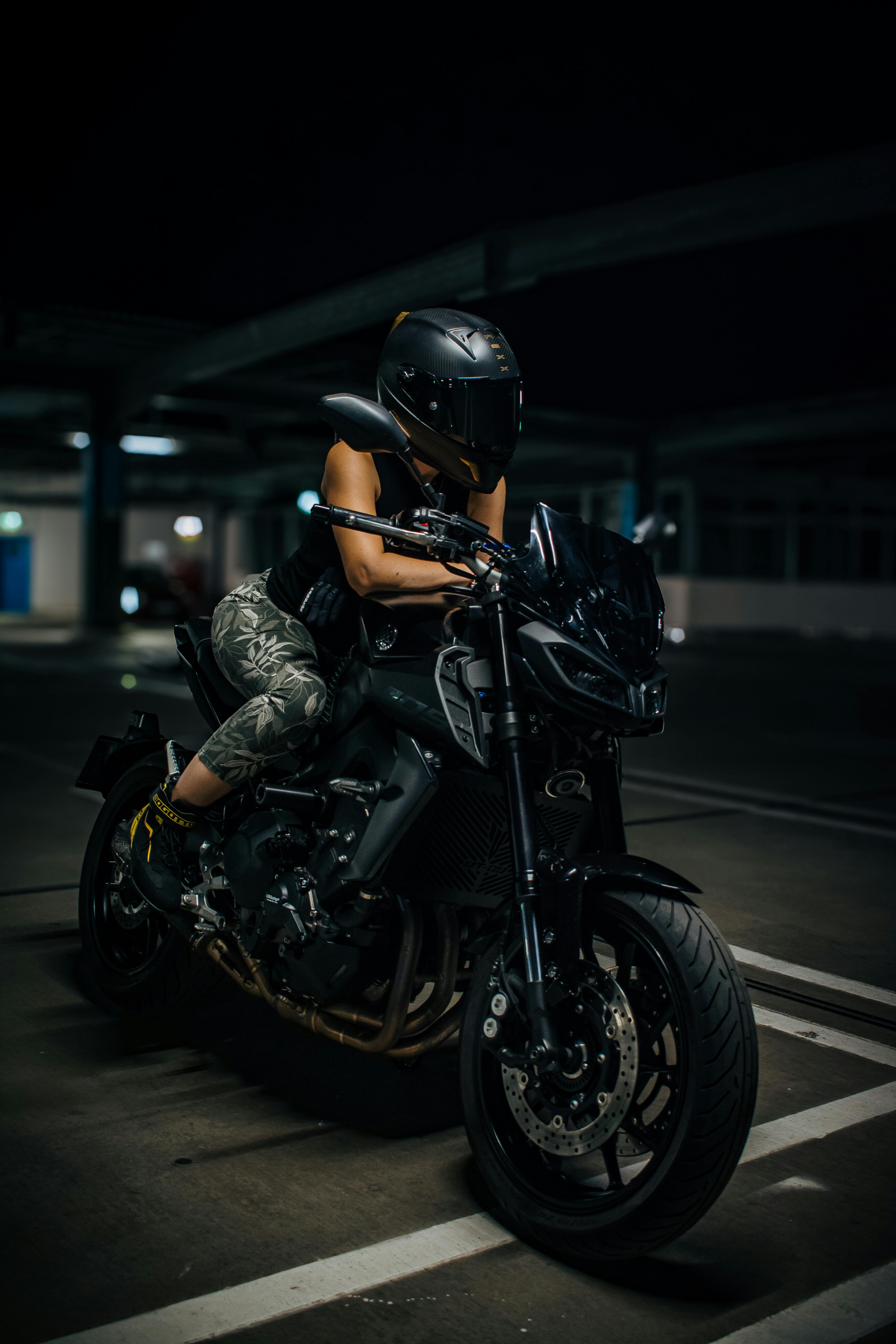 une femme avec un casque de moto noir sur une moto noir